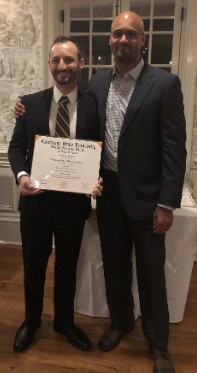 Dr. Anthony DiGiorgio holding a framed certificate at his 2019 neurosurgery graduation.